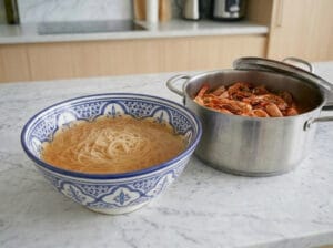 Pouring shrimp broth over the vermicelli