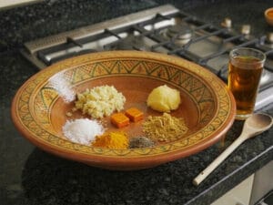 A traditional Moroccan bowl containing spices to marinate the chicken and a cup of saffron