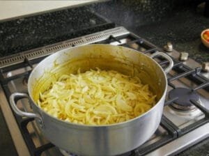 Adding onion slices to the broth in the pot to make the Dghmira (onion and sauce mixture)