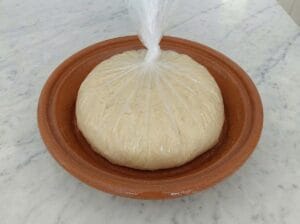 Dough wrapped in plastic inside the mixing bowl in the kitchen