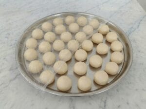 Dough balls arranged on a round baking tray in the kitchen