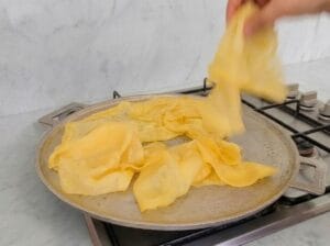 Separating the cooked dough layers so each layer can finish cooking around the edges on the baking griddle