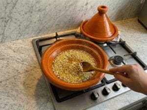 "Finely chopped onions sizzling in oil within a traditional Moroccan clay tagine