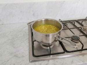 Preparing saffron-infused chicken broth in a separate pot over the stovetop
