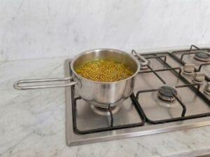 Cooking fenugreek separately with chicken broth in a pot over the stovetop