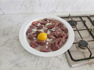 Soaking chicken liver in lemon juice and garlic in a dish on the kitchen countertop