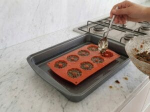 Pouring the chicken liver and egg mixture into silicone molds placed in a water bath on a baking tray