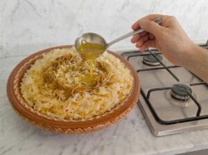 Placing a layer of trid in the Moroccan mixing bowl and soaking it with the thickened broth