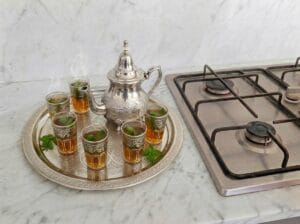 A traditional Moroccan tea tray with a Moroccan teapot and glasses filled with fresh mint tea placed on the kitchen countertop