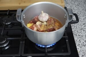 A pressure cooker with Tangia-style meat and whole garlic cloves