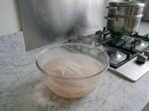 Chinese vermicelli noodles soaking in a bowl of hot shrimp stock