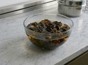 Black fungus mushrooms soaking in hot water in a glass bowl