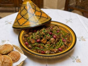 A yellow Moroccan serving tagine with cooked chicken liver, onions, green peppers, and spices