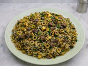 large plate containing Chinese vermicelli mixed with spices, olives, and chopped liver
