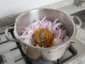 A pot containing sliced onions seasoned with aromatic spices