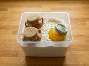 "A traditional clay jar of Smen (aged butter) next to a jar of melted Smen buried in a container of flour
