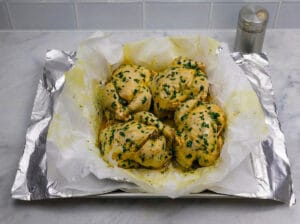 placing the chicken in a baking tray with parchment paper and aluminum foil