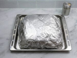 closing the aluminum foil on the seasoned and stuffed chicken