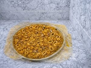 "Moroccan fish pastilla (bastilla) in a baking dish, featuring layers of crispy warqa pastry, filled with vermicelli noodles, and topped with perfectly cooked white calamari