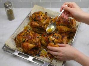 basting the roasted chicken with oil using a spoon