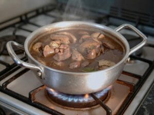 Boiled chicken liver in water with bay leaves and garlic in a stainless steel pot