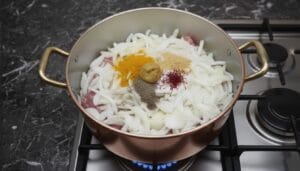 Pot of couscous meat stew with sliced onions, saffron, and aromatic spices.