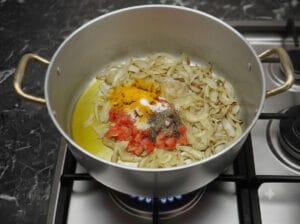 A pot of caramelized onions with diced tomato pieces