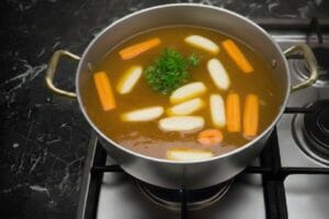 A pot of couscous broth with fresh, raw vegetables