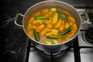 Adding fresh vegetables to the simmering couscous broth