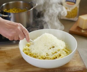 A large bowl classic fettuccine pasta dish topped with generous shaved Parmesan cheese