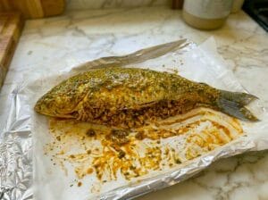 A baking tray lined with parchment paper, featuring a stuffed fish