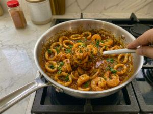 A pan filled with calamari rings simmering in a rich tomato sauce