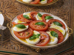 Sliced heirloom tomatoes with slices of burrata, basil leaves, and olive oil