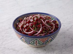 Cubed beetroot with sliced red onions and parsley in a large serving bowl