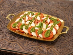Sliced tomatoes and buffalo mozzarella on a serving plate with pesto sauce