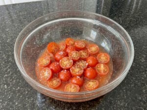 Half tomatoes with their juices in a glass bowl.