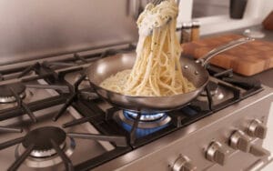 A pan of fettuccine pasta tossed in a creamy white sauce