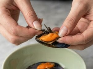 Hands cleaning mussels and removing the beard