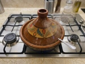 A spoon placed inside the tagine with the lid closed over it to allow steam to escape