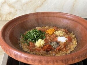 Tagine with oil, finely chopped golden-brown onion, well-cooked melted tomatoes, spices, and finely chopped parsley