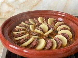 Red earthenware tagine with neatly and elegantly arranged kofta slices and patties