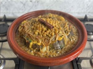 Conger eel fish with onions and raisins boiling over the fire in the tajine